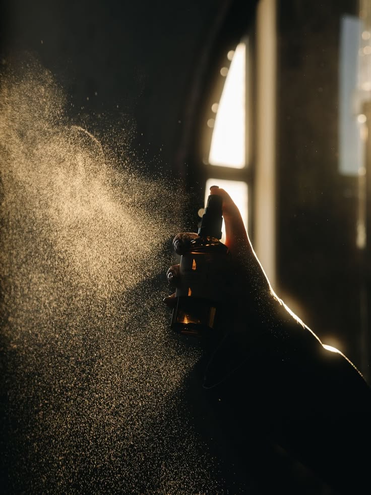 A fragrance caught mid-spray in dramatic light